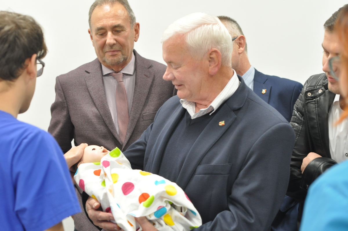 Władysław Gumieniak tuli fantom noworodka, przygląda się dyrektor szpitala Ryszard Rudnik.